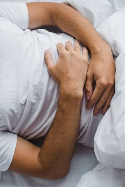 Colpo ritagliato di uomo che soffre di dolore addominale a letto — Foto stock