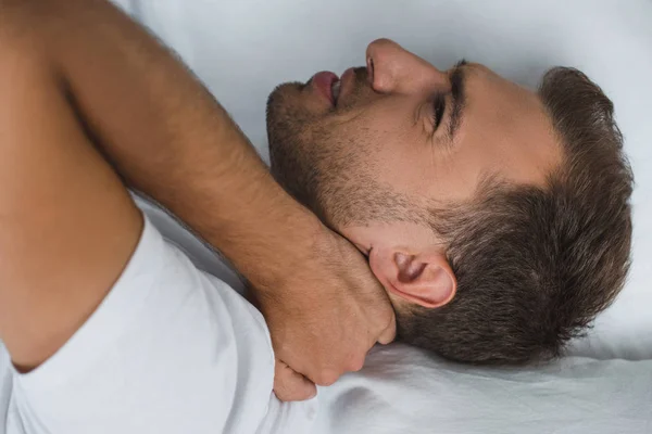 Человек лежит в постели и страдает от боли в шее — стоковое фото