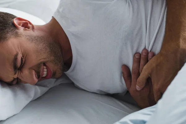 Cropped shot of man suffering from abdominal pain on bed — Stock Photo
