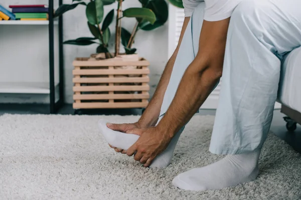 Colpo ritagliato di uomo seduto sul letto e affetto da dolore ai piedi — Foto stock