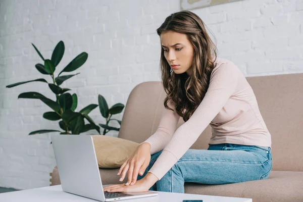 Young woman having pain in hand while using laptop at home — Stock Photo