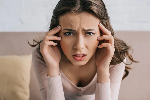 Close-up view of young woman suffering from headache and looking at camera — Stock Photo