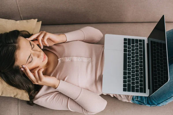 Draufsicht auf junge Frau mit Kopfschmerzen mit Laptop mit leerem Bildschirm zu Hause — Stockfoto
