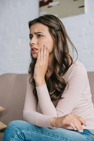 Jeune femme souffrant de douleur à la mâchoire et regardant loin à la maison — Photo de stock