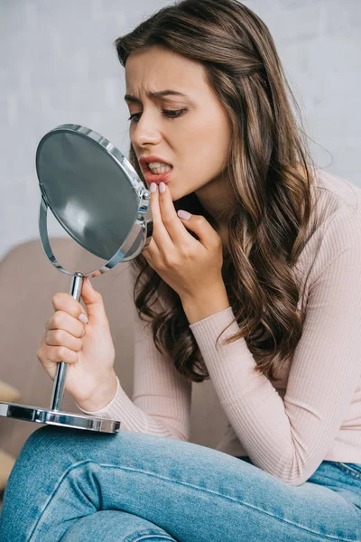 Attractive young woman with tooth pain sitting and looking at mirror — Stock Photo