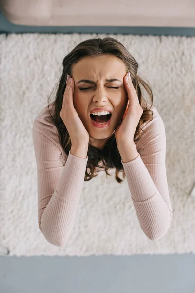 Overhead view of young woman screaming and suffering from headache — Stock Photo
