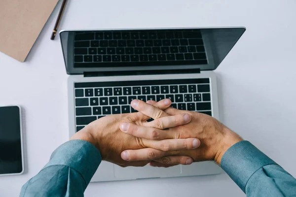 Partial top view of man stretching hands while using laptop — Stock Photo