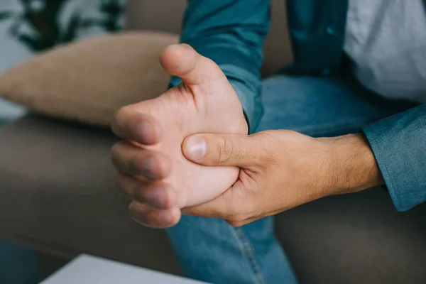 Primer plano vista parcial del hombre que tiene dolor en la muñeca - foto de stock