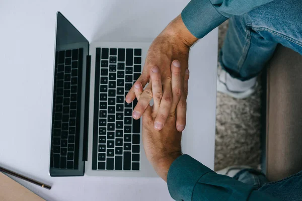 Cropped shot of man stretching hands while using laptop — Stock Photo