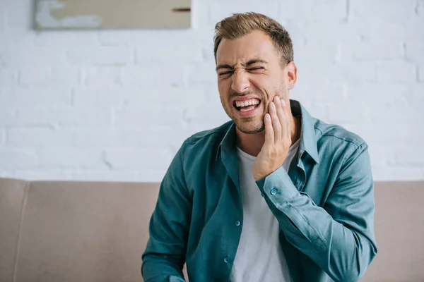 Young man suffering from tooth pain at home — Stock Photo