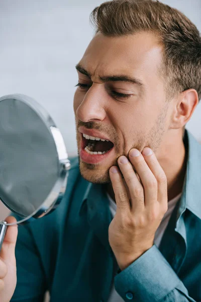 Junger Mann mit Zahnschmerzen blickt in Spiegel — Stockfoto