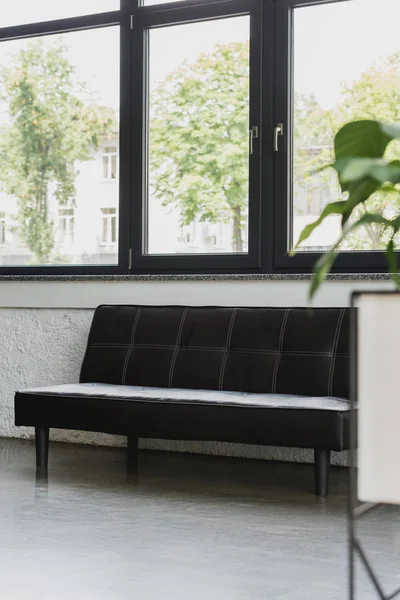Empty modern black couch near window in modern office — Stock Photo