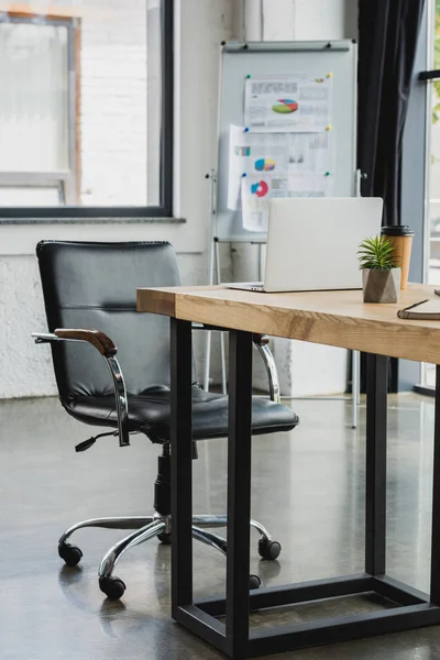 Laptop na mesa e quadro branco com gráficos de negócios no escritório moderno — Fotografia de Stock