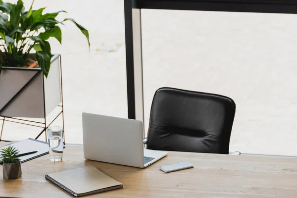 Laptop and smartphone on wooden table in modern office — Stock Photo