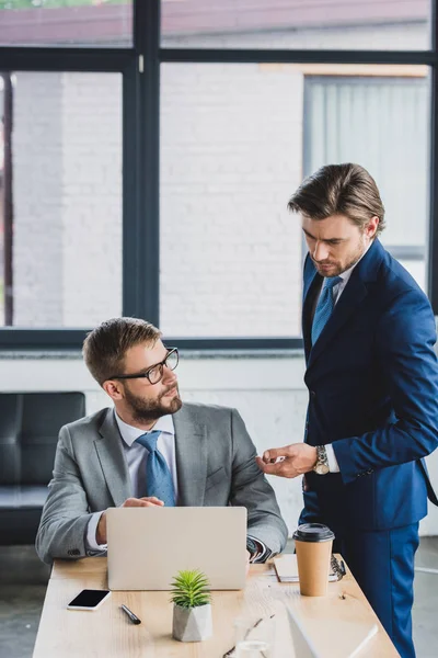 Gutaussehende junge Geschäftsleute benutzen Laptop und diskutieren Projekt im Büro — Stockfoto