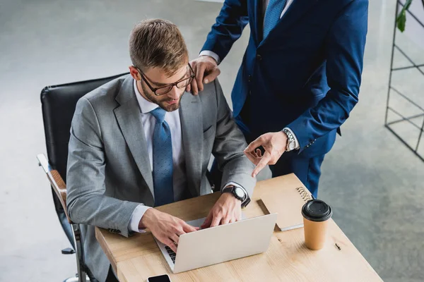 Cropped shot of young businessmen using laptop while working together in office — Stock Photo