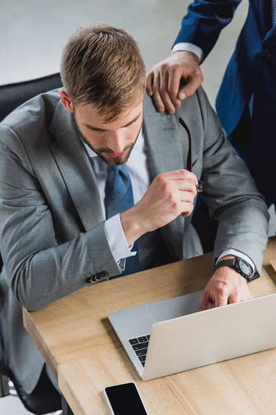 Vue grand angle de jeune homme d'affaires concentré en utilisant un ordinateur portable dans le bureau — Photo de stock