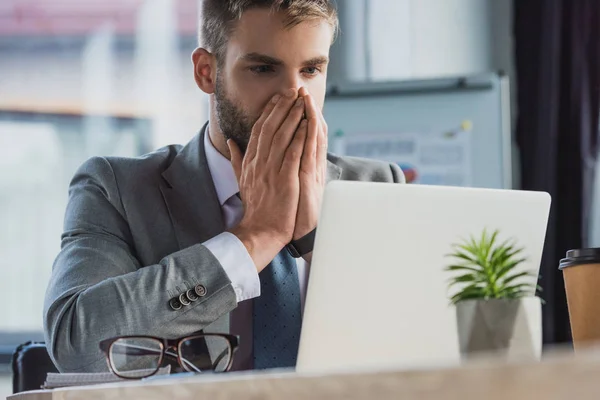 Sorprendido joven empresario utilizando el ordenador portátil en la oficina - foto de stock