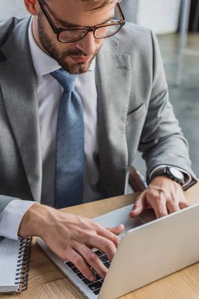 Vue grand angle de l'homme d'affaires dans les lunettes à l'aide d'un ordinateur portable au bureau — Stock Photo