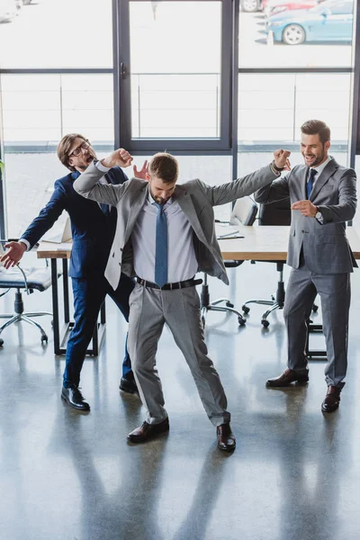 Excités jeunes hommes d'affaires dansant et célébrant dans le bureau — Photo de stock