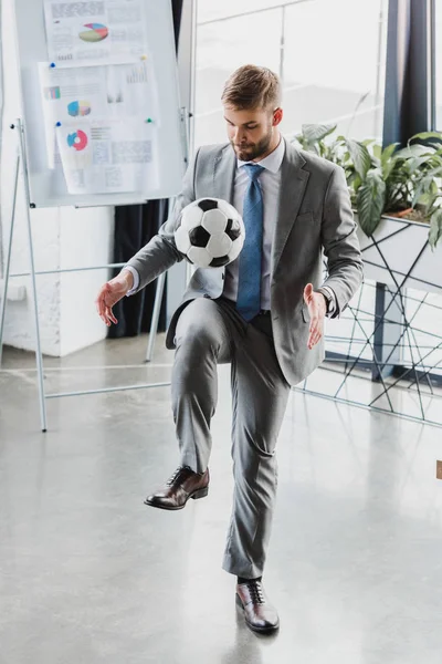 Visão de comprimento total do jovem empresário em desgaste formal jogando com bola de futebol no escritório — Fotografia de Stock