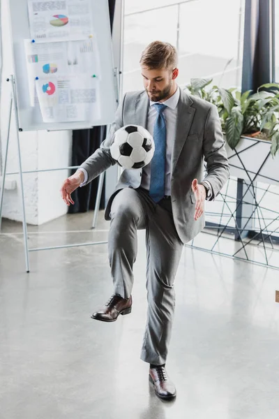 Vista completa del joven empresario en ropa formal jugando con pelota de fútbol en la oficina — Stock Photo