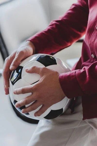 Cropped shot of businessman holding soccer ball in office — Stock Photo