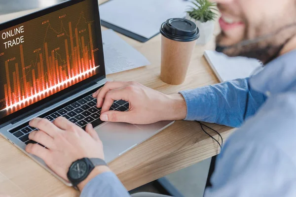 Recortado disparo de sonriente hombre de negocios en auriculares utilizando el ordenador portátil con sitio web de comercio en línea en la pantalla - foto de stock