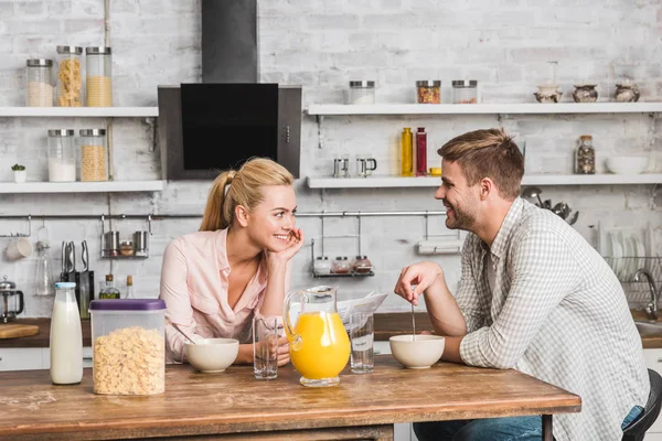 Casal tomando café da manhã na cozinha, namorada segurando jornal — Fotografia de Stock
