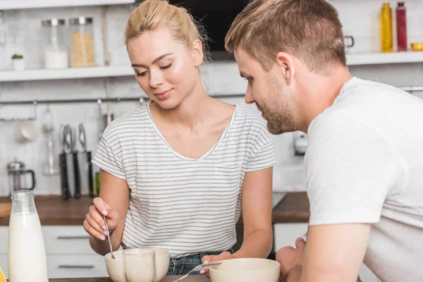 Молодая пара в повседневной одежде завтракает на кухне — стоковое фото