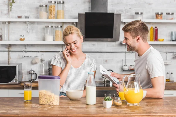 Girlfriend talking by smartphone during breakfast in kitchen — Stock Photo