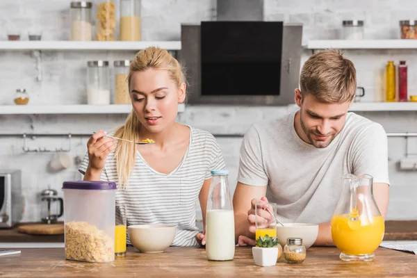Пара має кукурудзяні пластівці з молоком на сніданок на кухні — стокове фото