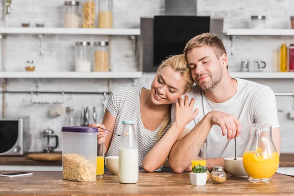Пара завтракает и обнимается с закрытыми глазами на кухне — стоковое фото