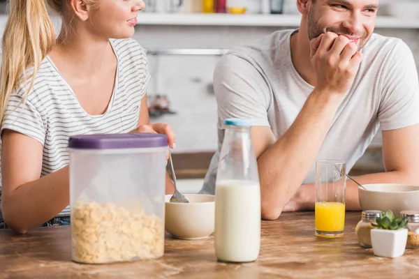 Coppia che fa colazione in cucina, cornflakes e bottiglia di latte in tavola — Foto stock