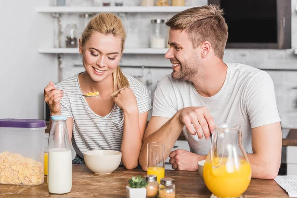 Couple petit déjeuner et manger des flocons de maïs avec du lait dans la cuisine — Photo de stock