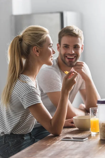 Novio feliz mirando a la novia durante el desayuno en la cocina - foto de stock