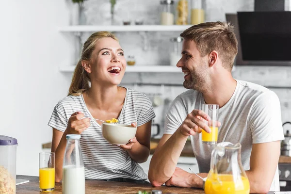Пара завтракает и смеется на кухне — стоковое фото