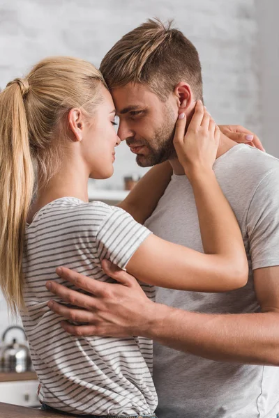 Vue latérale de couple étreignant dans la cuisine — Photo de stock