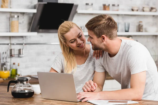 Smiling couple working together with laptop in morning and looking at each other — Stock Photo