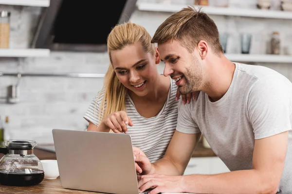 Paar schaut gemeinsam in Küche auf Laptop — Stockfoto