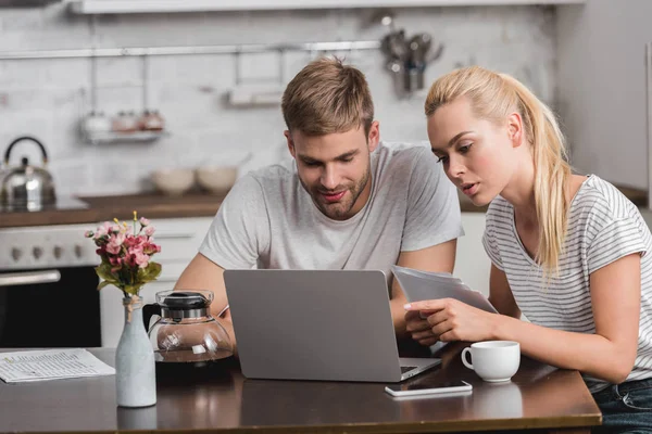 Coppia seduta e guardando il computer portatile in cucina — Foto stock