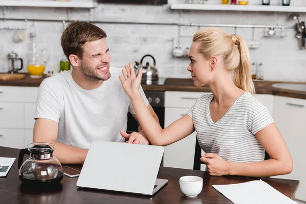 Emotional young woman slapping boyfriend during quarrel at home — Stock Photo