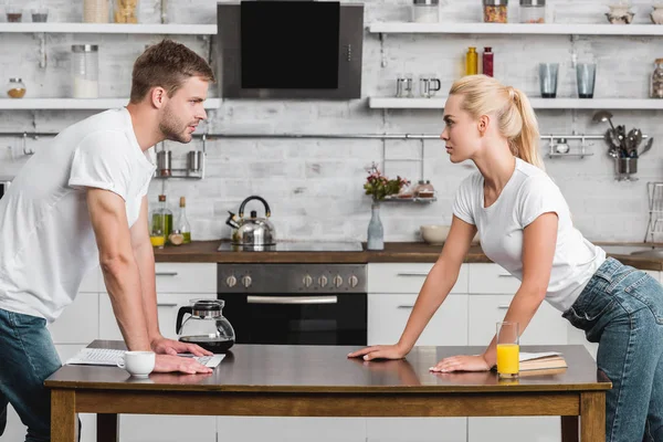 Вид сбоку страстной молодой пары, смотрящей друг на друга на кухне — стоковое фото