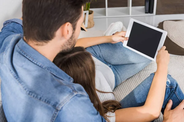 Rear view of young couple watching digital tablet with blank screen on sofa at home — Stock Photo