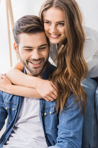 Nahaufnahme einer schönen lächelnden Frau, die ihren Freund umarmt, während sie zu Hause auf dem Boden sitzt — Stockfoto