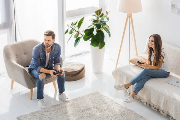Vista de ángulo alto de hombre joven molesto jugando videojuego con la novia sonriente en casa - foto de stock
