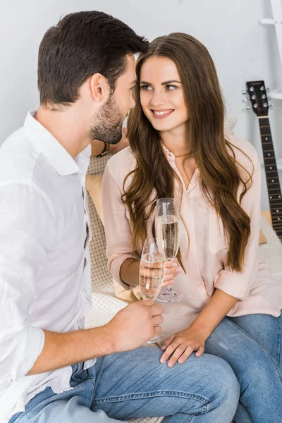 Glückliches Paar klimpert im neuen Zuhause auf dem Sofa mit Champagner — Stockfoto