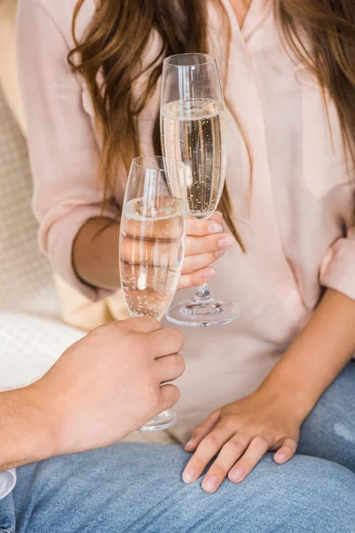 Partial view of couple clinking glasses of champagne on sofa at new home — Stock Photo