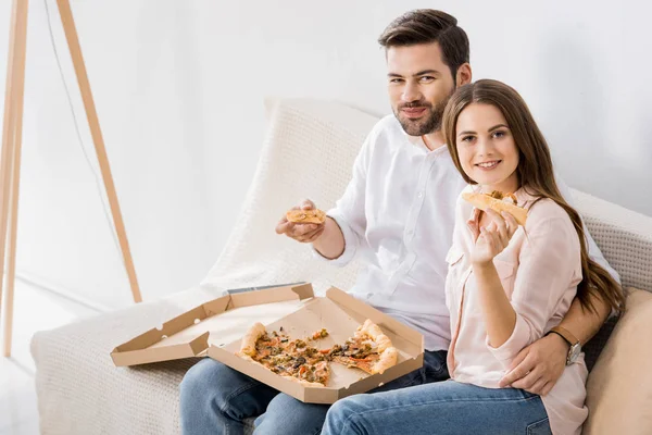 Retrato de jovem casal sorrindo comer pizza em casa — Fotografia de Stock