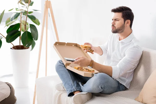 Mann isst Pizza, während er allein zu Hause fernsieht — Stockfoto